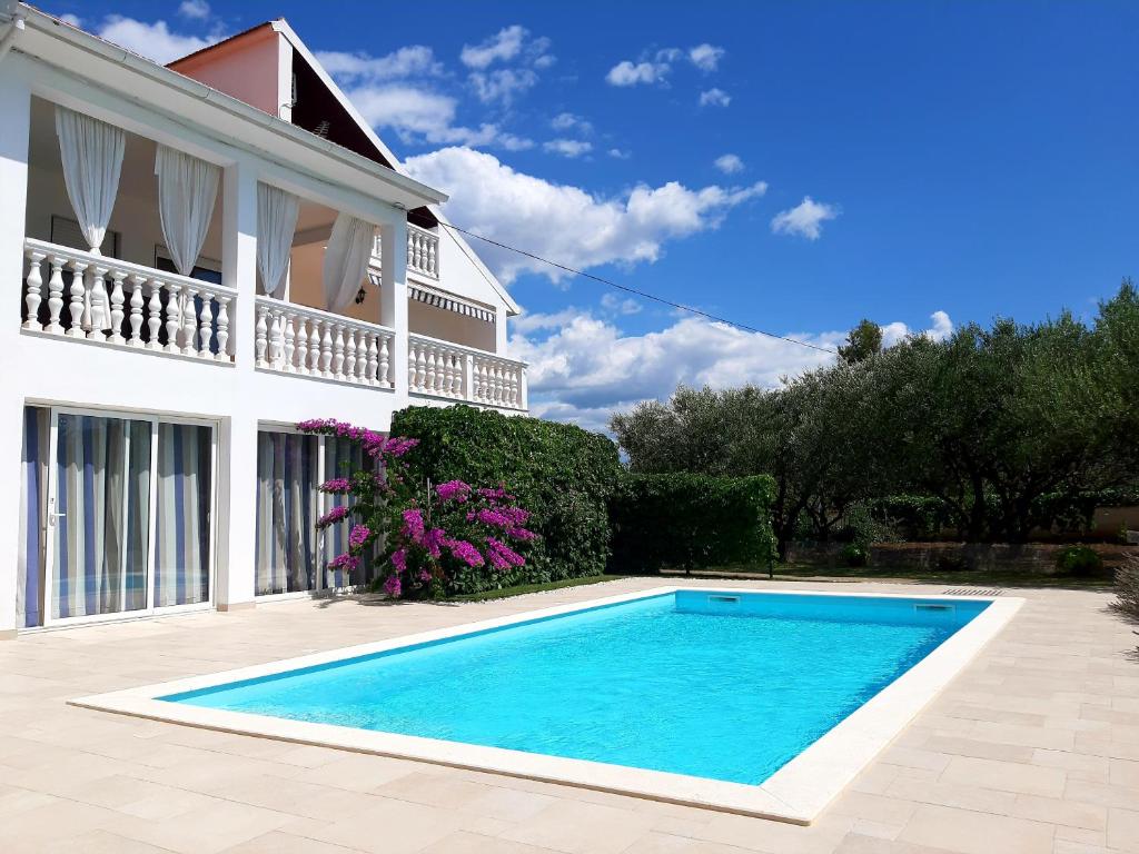 a swimming pool in front of a house at Holiday Home Villa Emma in Debeljak