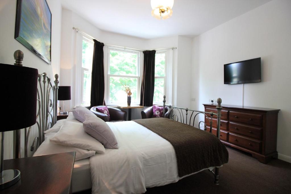 a bedroom with a bed and a desk and a television at Seafield House in Brighton & Hove