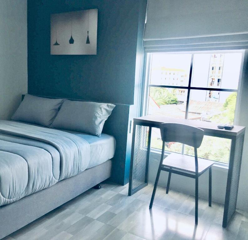 A compact bedroom pairs a double bed with a narrow desk beside a bright window.