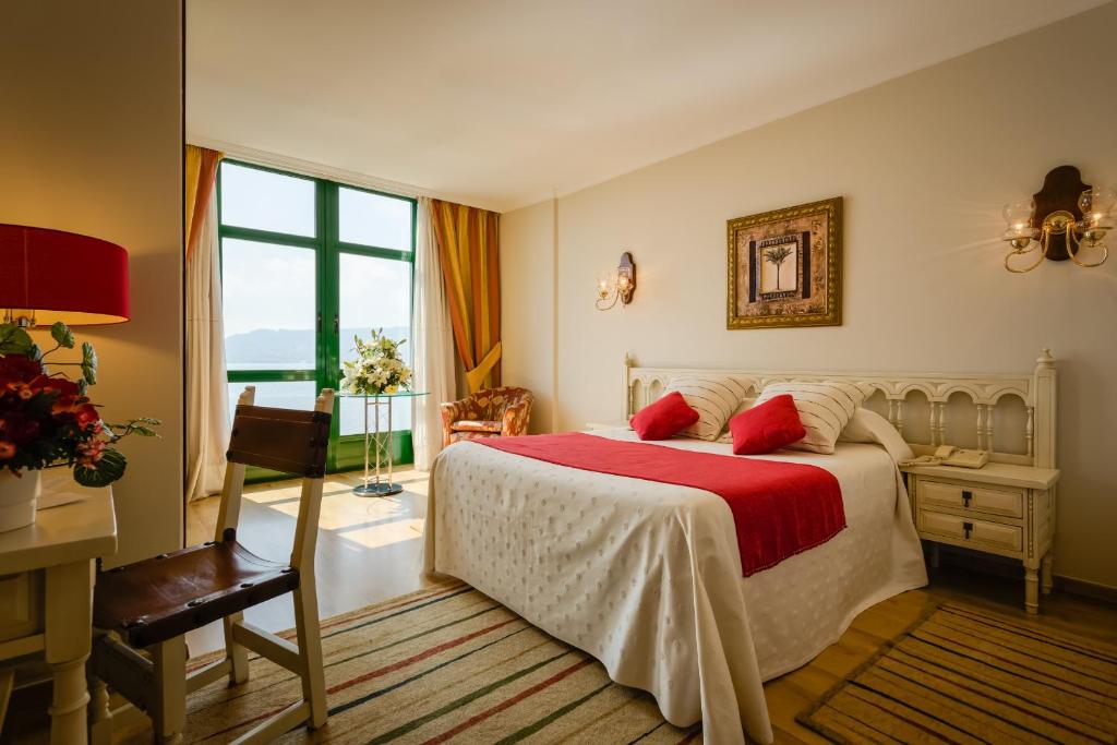 a bedroom with a bed and a large window at Hotel Stellamaris in Combarro