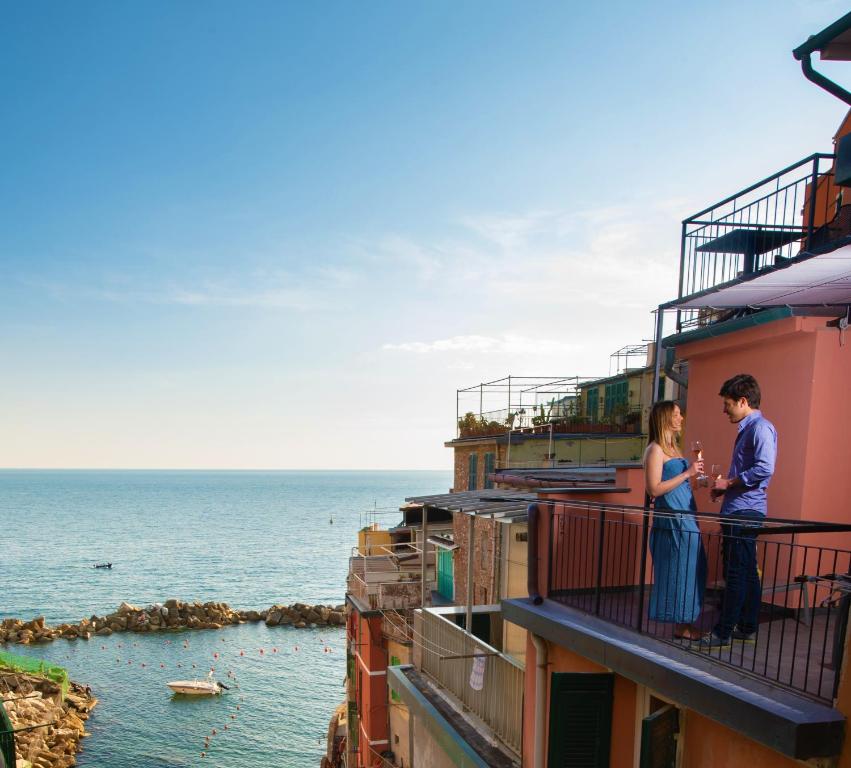 Una pareja de pie en un balcón con vistas al océano en Meb, en Riomaggiore