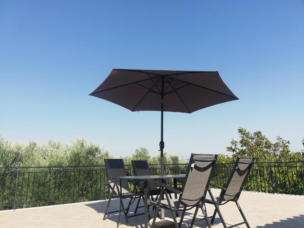 a table and chairs with an umbrella on a patio at Paliorouga Lodge Zakynthos in Langadhákia