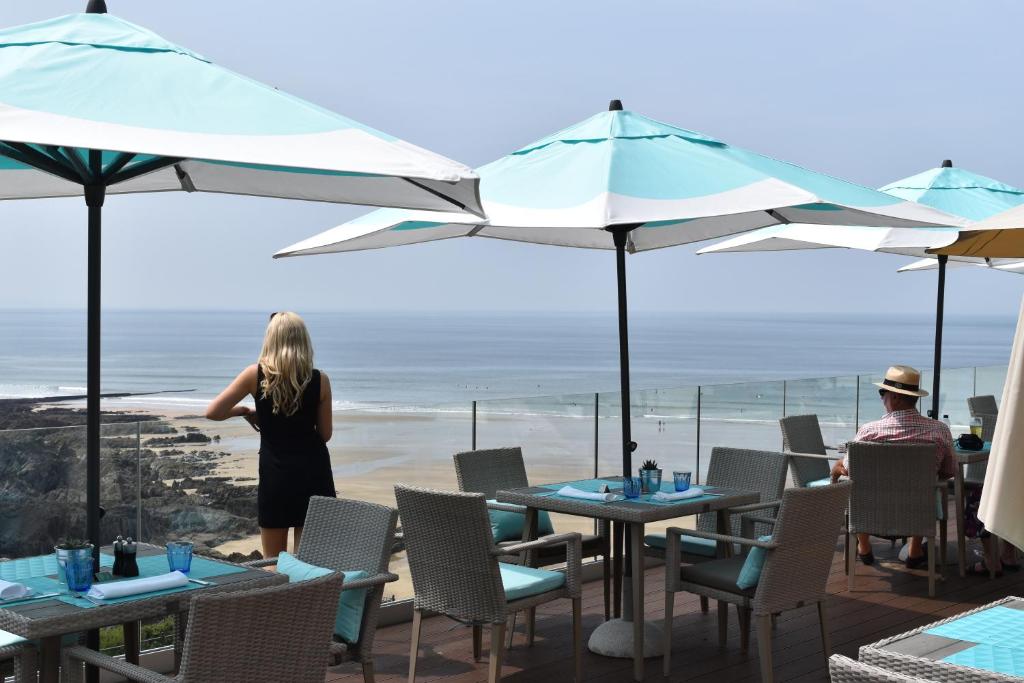 a woman standing on a patio with tables and umbrellas at Watersmeet Hotel in Woolacombe