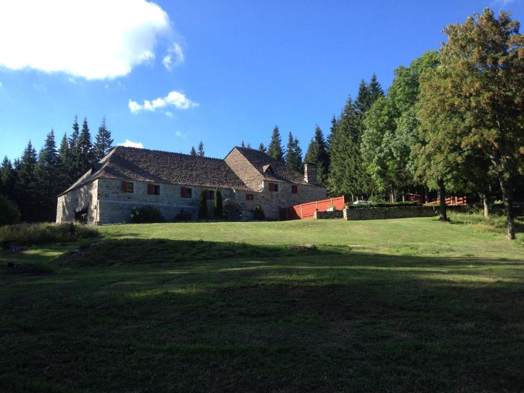 ein großes Haus auf einem Grasfeld neben einem Wald in der Unterkunft Domaine du Lac Ferrand in Saint-Cirgues-en-Montagne