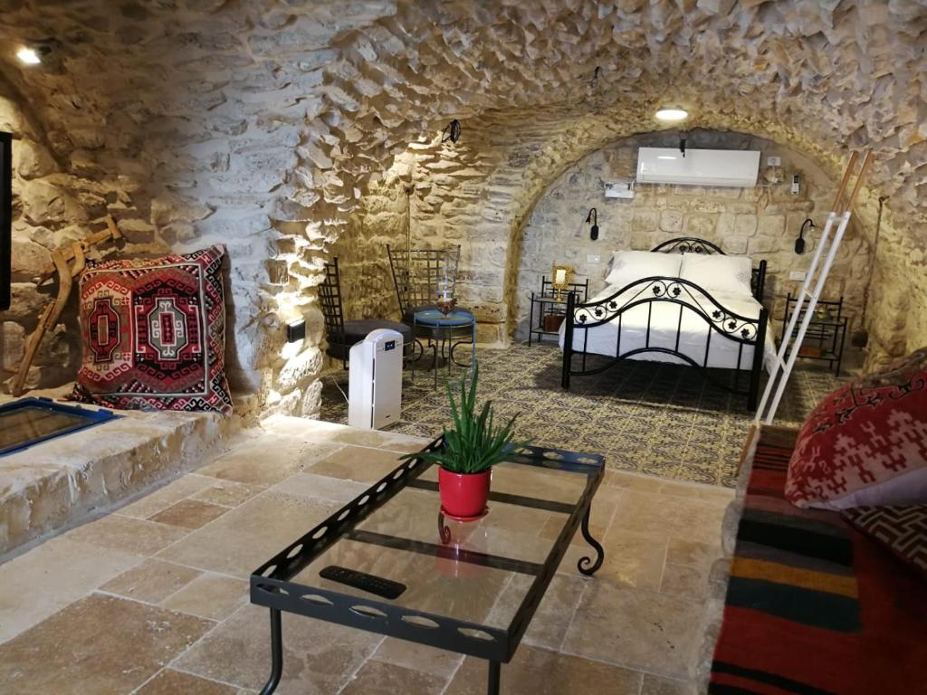 ein Schlafzimmer mit einem Bett und einem Tisch in einem Steinzimmer in der Unterkunft בבית של סבתא וסבא in Safed