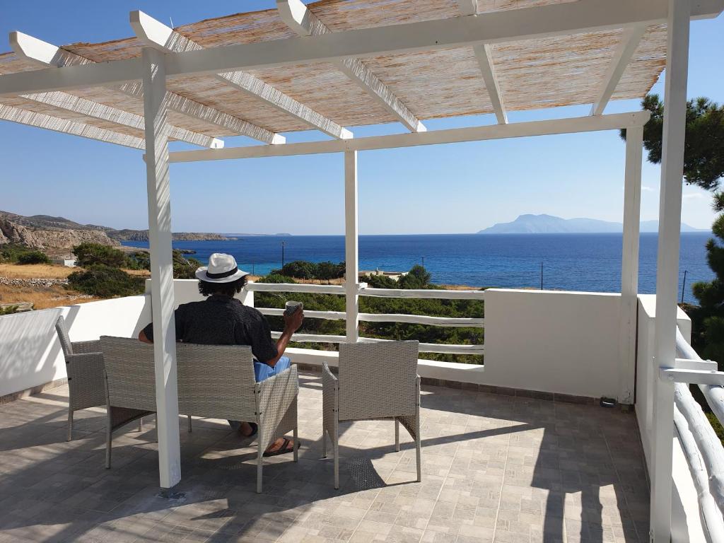 een man in een stoel die uitkijkt op de oceaan bij Kathys Island Retreat in Adia