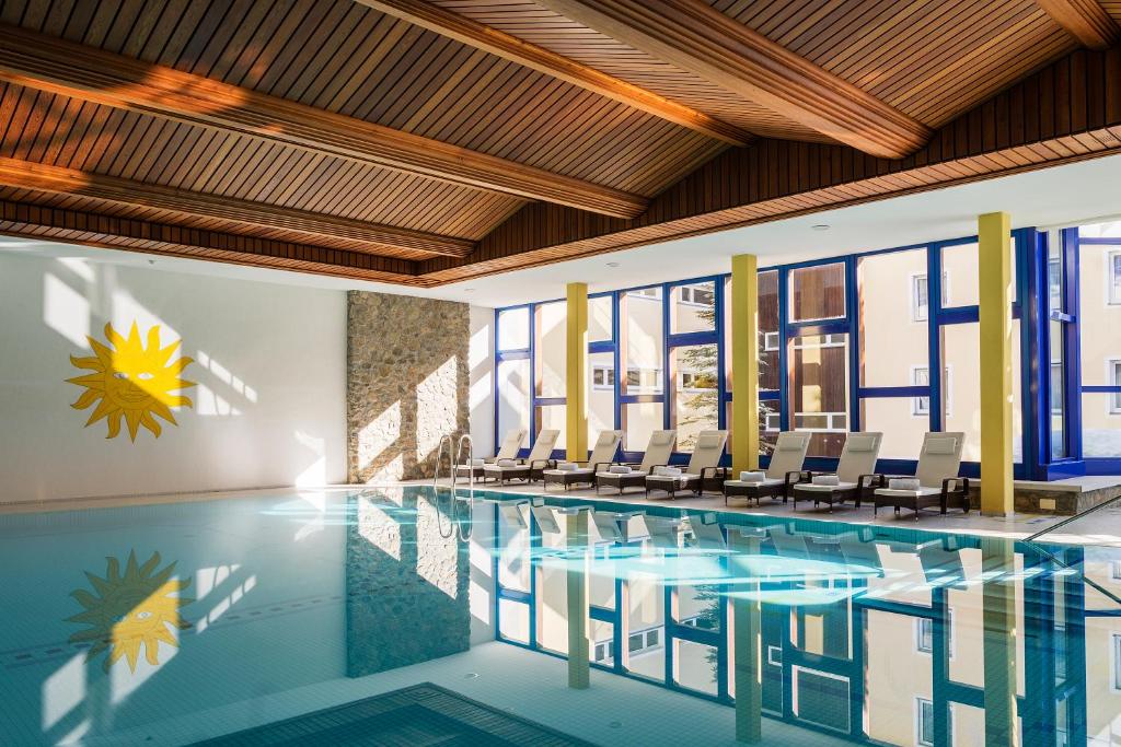 a swimming pool with chairs in a building at Hotel Europa Suites St Moritz in St. Moritz
