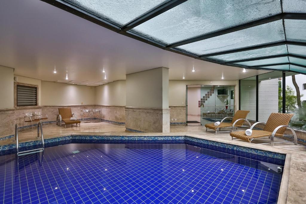 uma piscina interior com cadeiras e uma mesa em Transamerica Paradise Garden em São Paulo