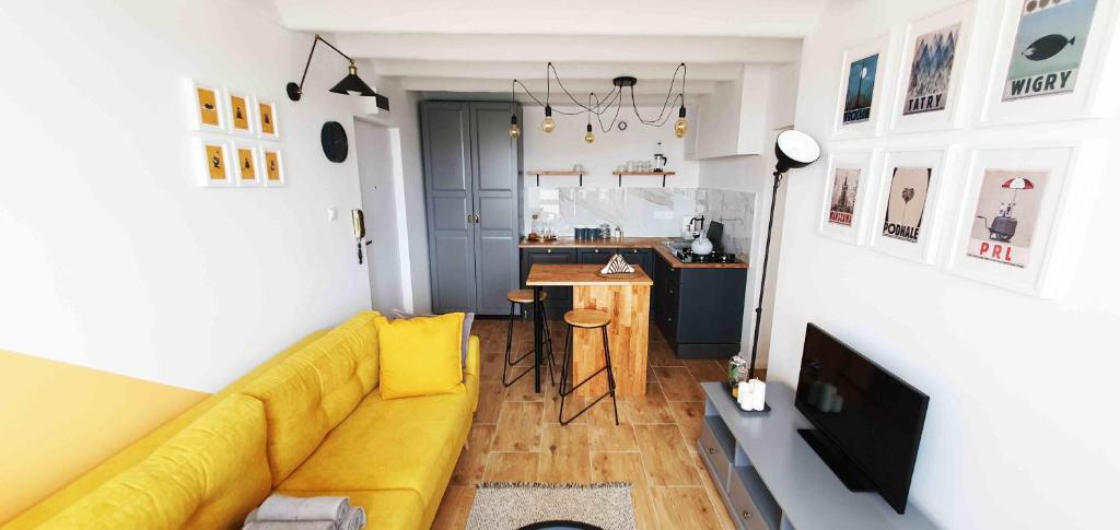 a living room with a yellow couch and a kitchen at CityBrejk Zaporoska Wrocław in Wrocław