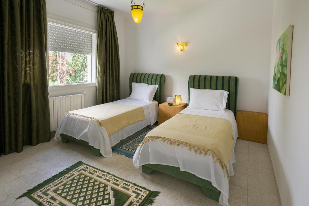 a bedroom with two beds and a window at Villa Phoenicia in Hammamet