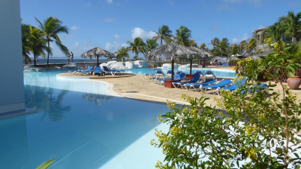 een zwembad van het resort met stoelen en parasols bij Appartement proche de la mer Ty Manganao in Saint-François