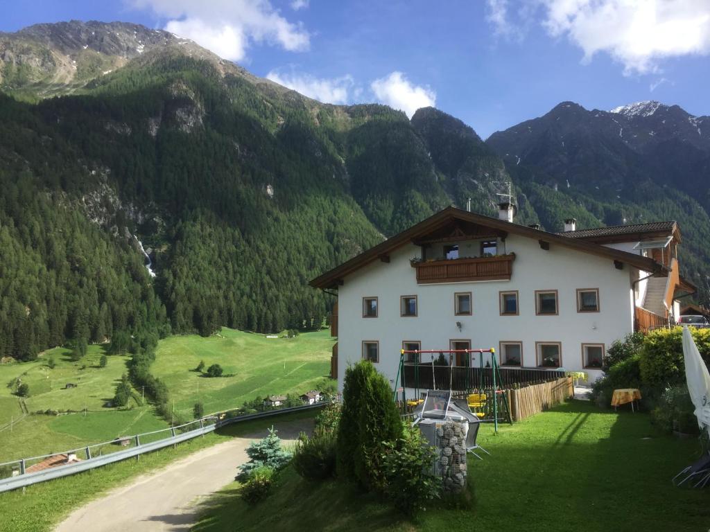 ein großes weißes Gebäude mit Bergen im Hintergrund in der Unterkunft Ferienhof Mairulrich in Martell