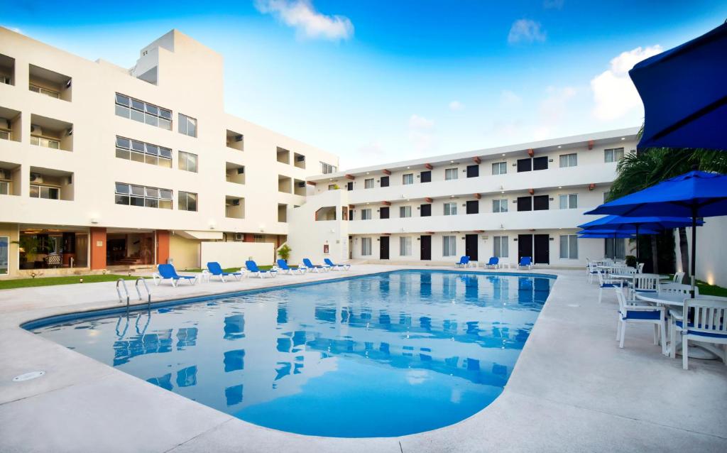 una piscina frente a un hotel con sillas y sombrillas en Hotel Bonampak en Cancún