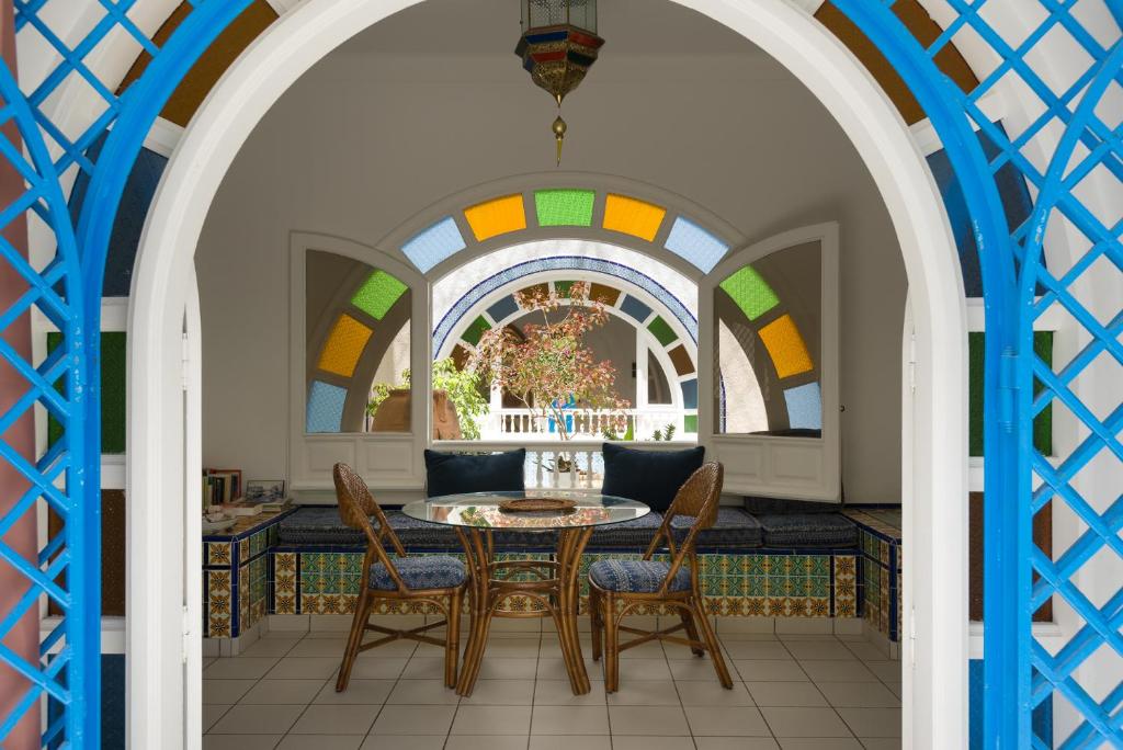 ein Esszimmer mit einem Tisch, Stühlen und einem Fenster in der Unterkunft Villa Phoenicia in Hammamet