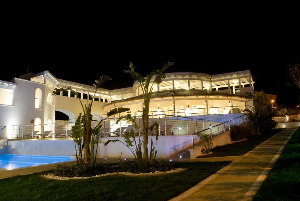 a large white building at night with a pool at Ganimede Hotel in Sperlonga