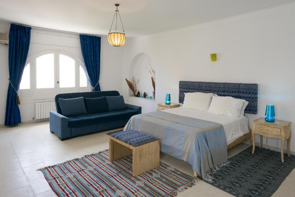 a bedroom with a bed and a blue couch at Villa Phoenicia in Hammamet