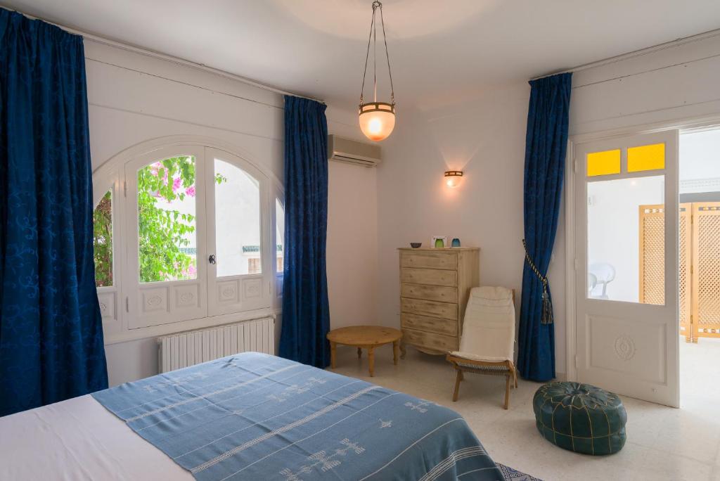 a bedroom with blue curtains and a bed and a dresser at Villa Phoenicia in Hammamet