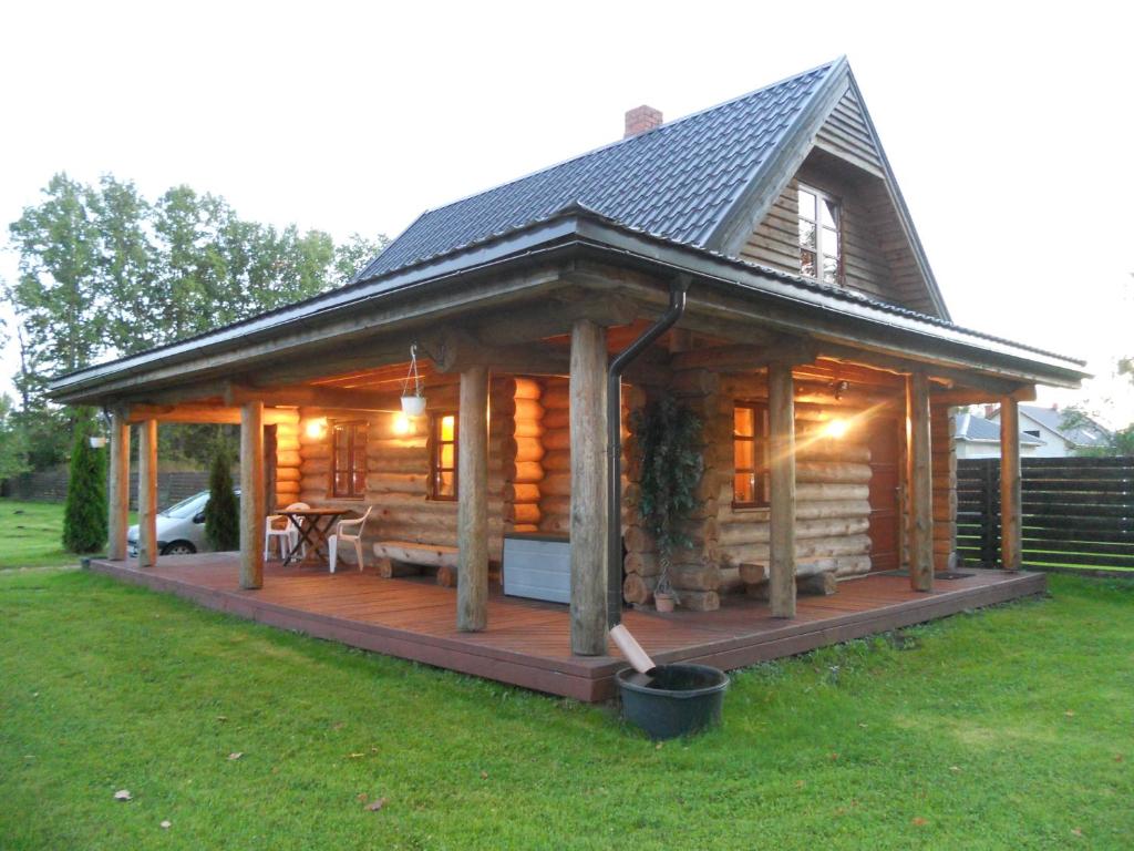 a large wooden cabin with a deck in the grass at Forest Edge Lodge in Riga