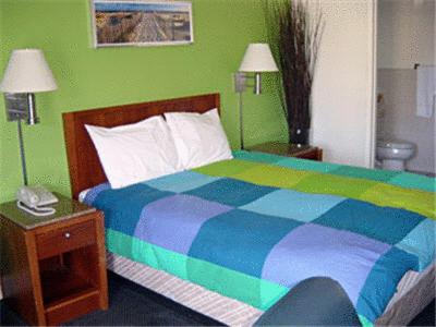Un dormitorio con una cama colorida y una pared verde en Sequoia Inn Redwood City, en Redwood City