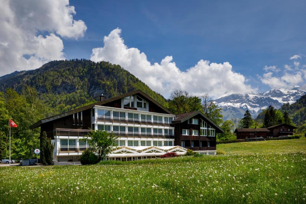 Ein Gebäude auf einem Feld mit Bergen im Hintergrund in der Unterkunft Hotel Klausenhof Flüeli in Flüeli