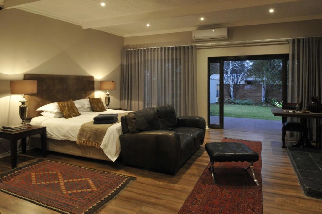 a bedroom with a bed and a couch and a chair at Kestell Stables in Bloemfontein