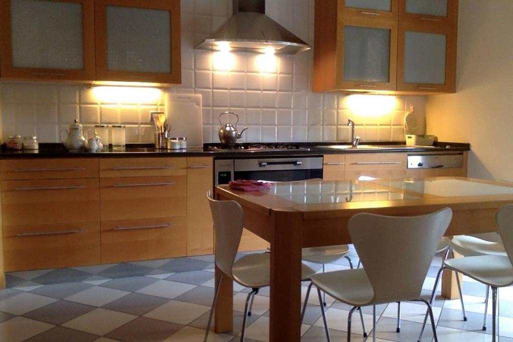 - une cuisine avec une table en bois et des chaises blanches dans l'établissement VASARI APARTMENT, à Vérone