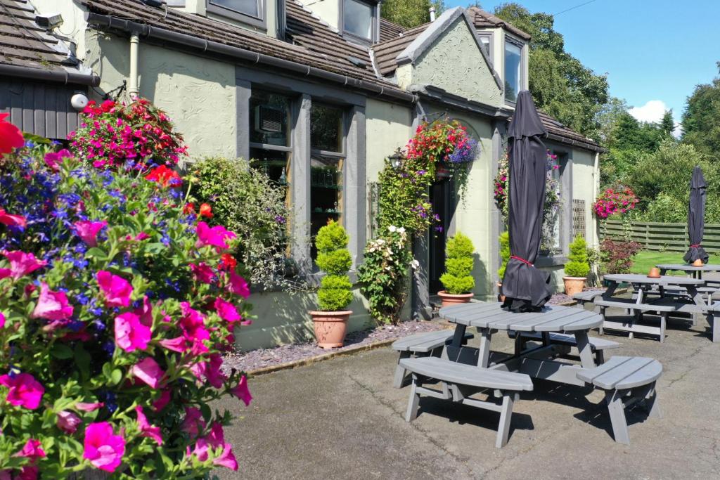 a patio with benches and flowers in front of a house at Auld Mill House Hotel in Dunfermline