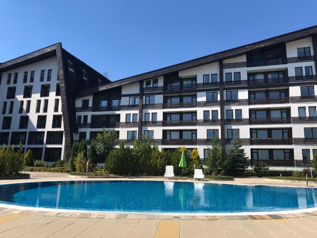a building with a swimming pool in front of a building at Apartman Maxim Lux in Razlog