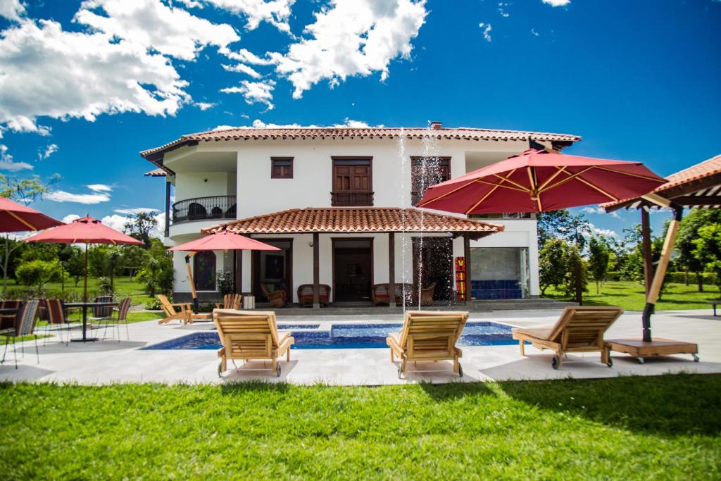 un patio con sillas y sombrillas frente a una casa en La Herencia Hotel, en Armenia