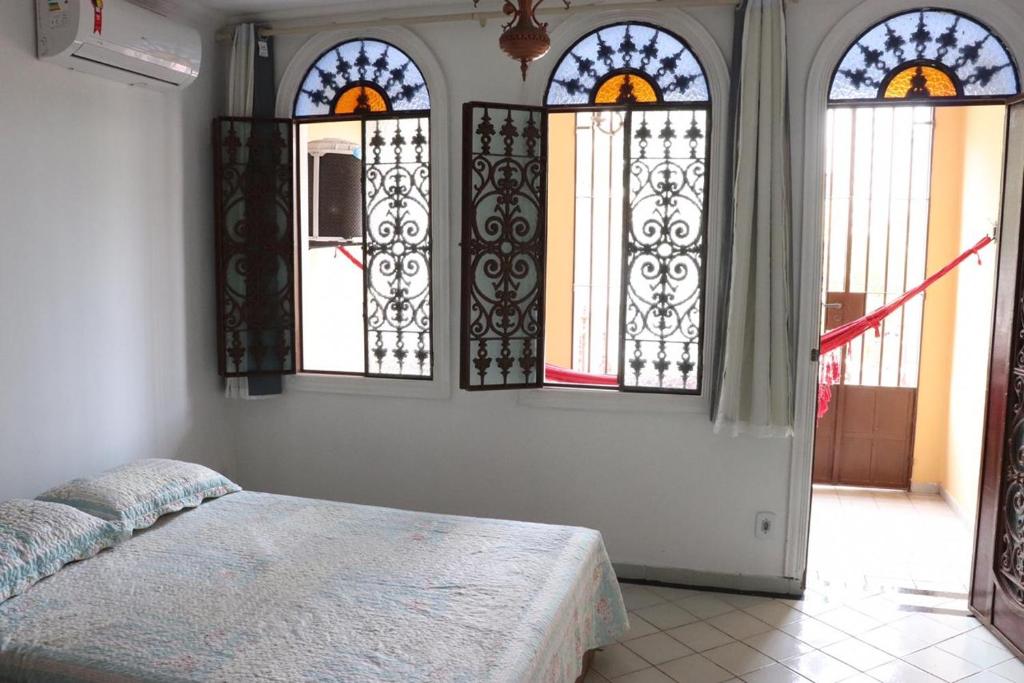 a bedroom with three stained glass windows and a bed at Casa da Josi - Pajuçara in Maceió