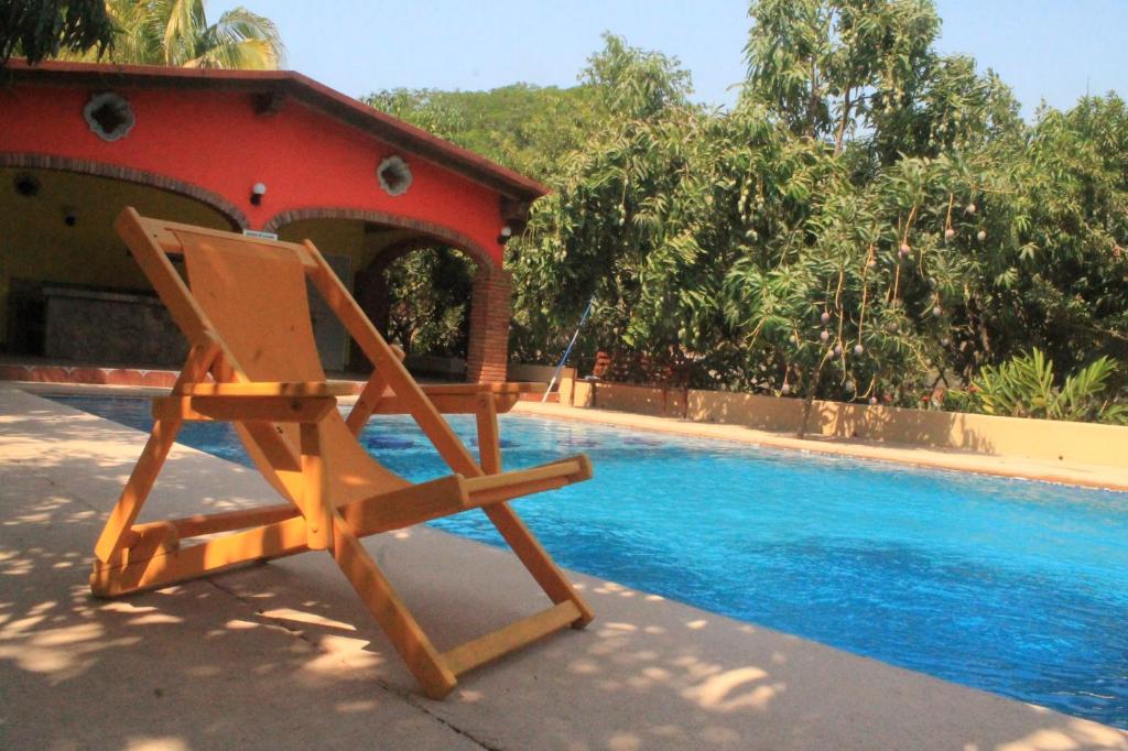 a wooden chair sitting next to a swimming pool at Quinta Comala Hotel & Villas in Comala