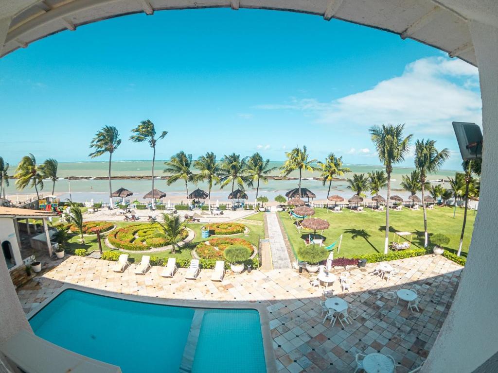 a view of the pool and beach from the balcony of a resort at Apartamentos Beira Mar Marinas Tamandare PRAIA DOS CARNEIROS in Praia dos Carneiros