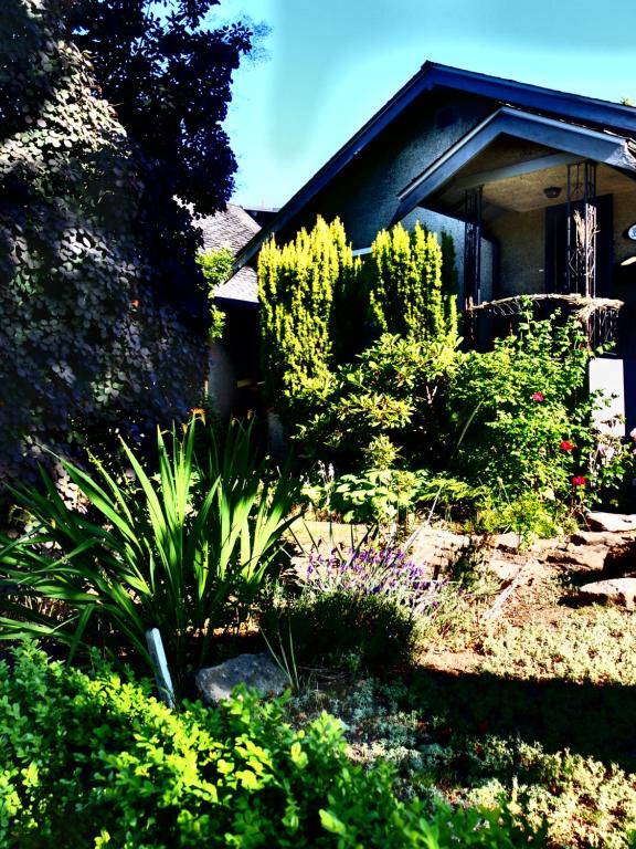 a garden with flowers and plants in front of a house at Compact private room, private bathroom, laundry & free parking in a lovely Vancouver neighborhood in Vancouver