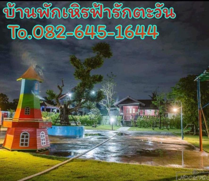 una casa luminosa in un parco di notte di บ้านฟ้ารักตะวัน a Petchaburi