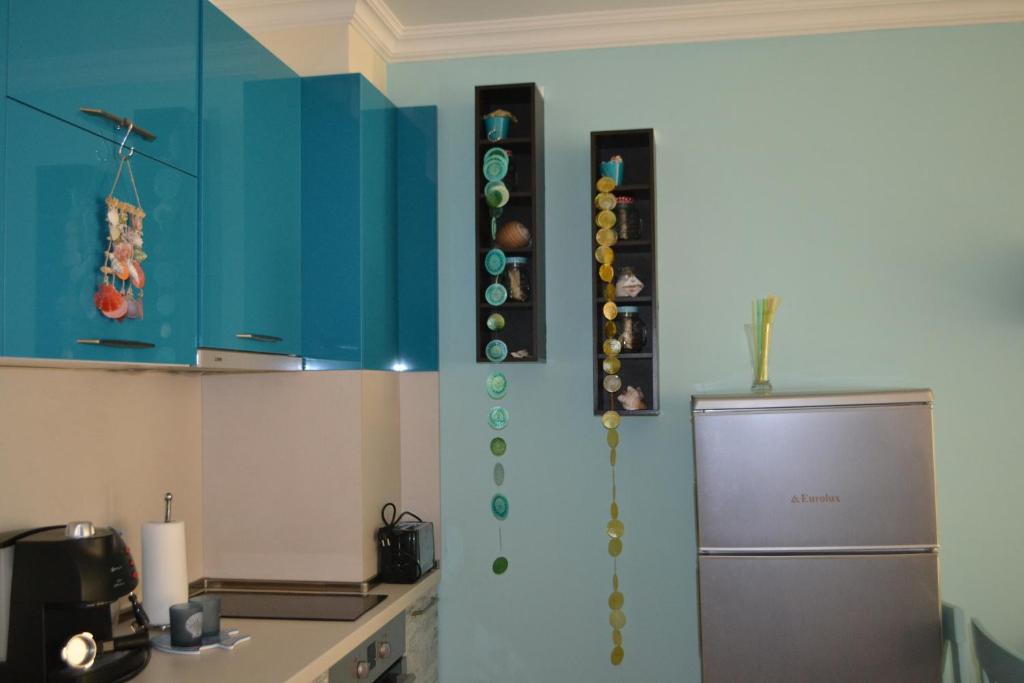 La cuisine est équipée de placards bleus et d'un réfrigérateur. dans l'établissement Apartment Aquamarine, à Bourgas