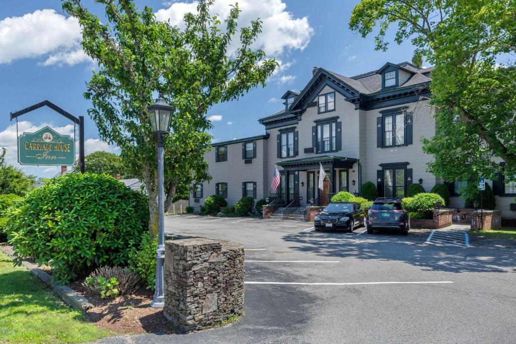 ein großes weißes Gebäude mit Autos auf einem Parkplatz in der Unterkunft The Carriage House Inn Newport in Middletown