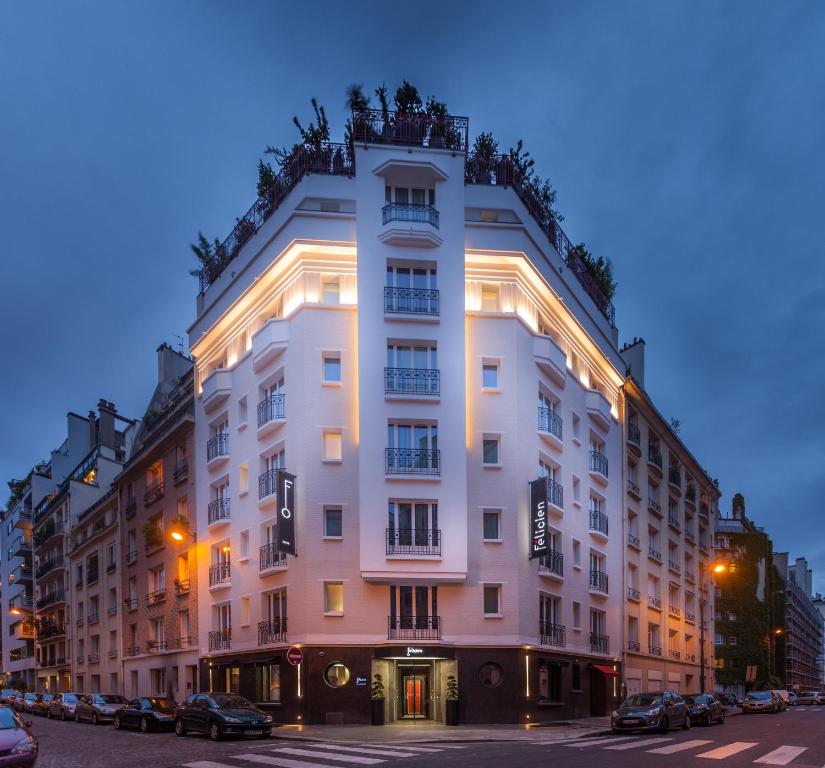 - un grand bâtiment blanc dans une rue de la ville la nuit dans l'établissement Hôtel Félicien & SPA, à Paris