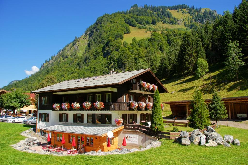 a large house with flowers in front of a mountain at Landhaus Spielmannsau in Oberstdorf