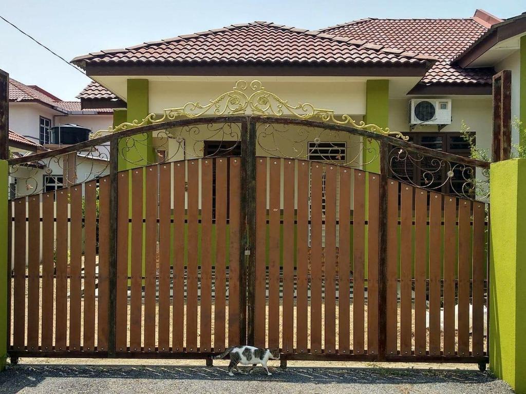 un chat debout devant une porte en bois dans l'établissement TokWan PCB Homestay, à Kota Bharu
