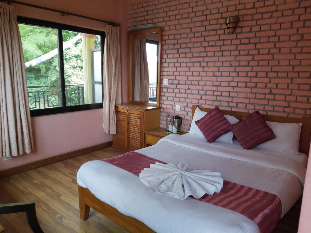 a bedroom with a bed and a brick wall at Hotel Valley View Inn in Nagarkot