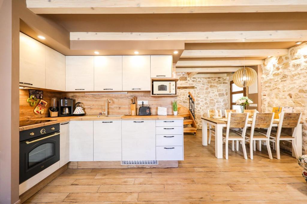 a kitchen with white cabinets and a table with chairs at Holiday house Ivana, Zadar, Vinjerac in Vinjerac