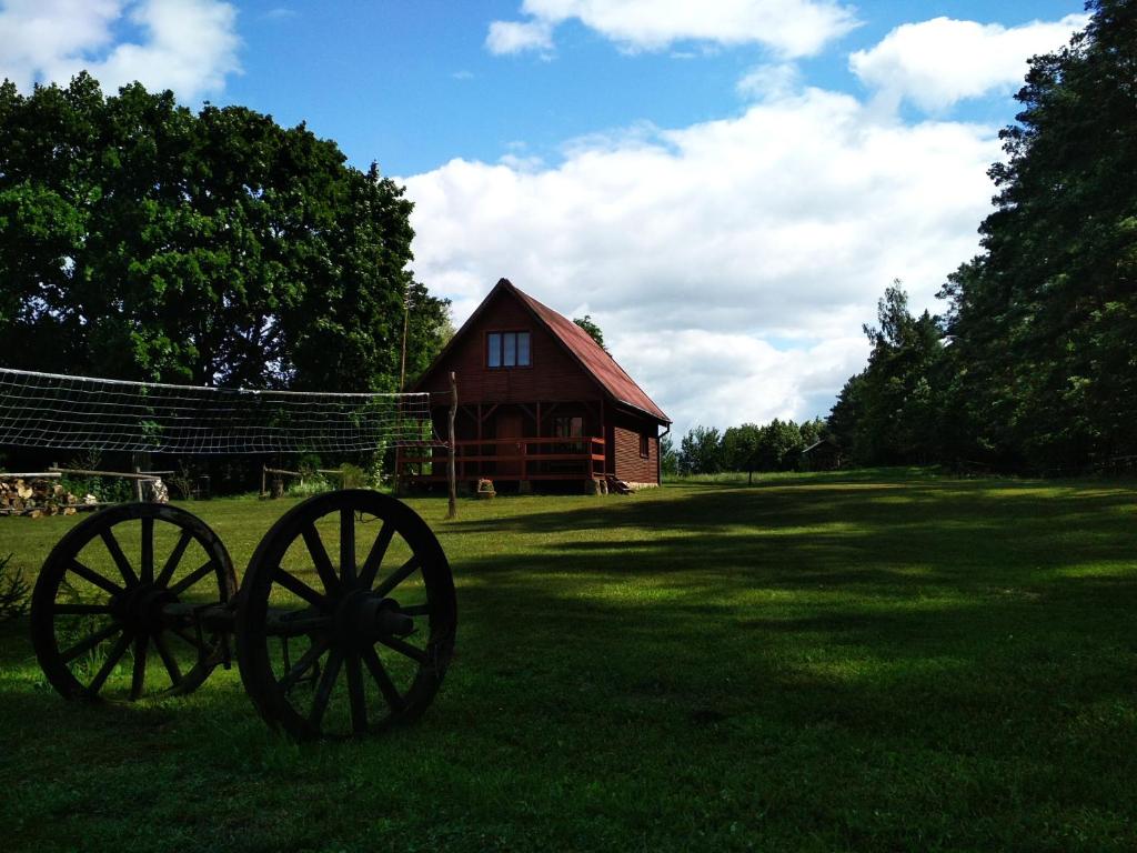 two wagon wheels in the grass in front of a barn at Domek całoroczny MARKO in Węgorzewo