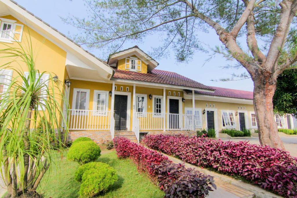 een geel huis met paarse bloemen ervoor bij Trans Bandara Residence in Sungairampah