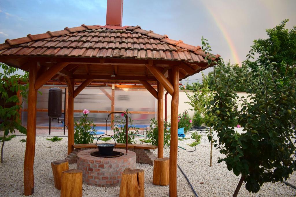 a wooden gazebo with a rainbow in the background at Tündérfátyol vendégház in Poroszló