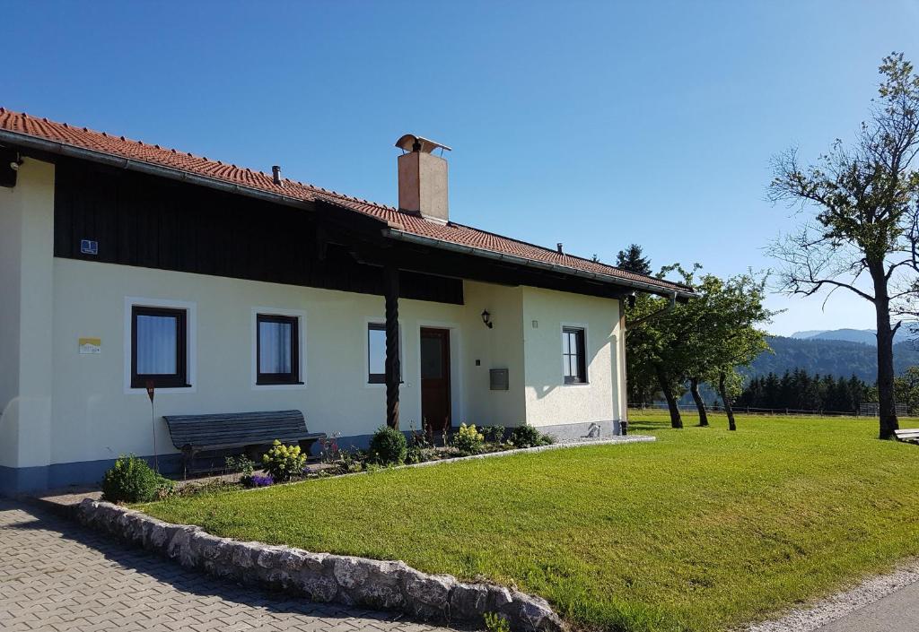 a white house with a bench in a yard at Ferienhaus am Riedl in Siegsdorf