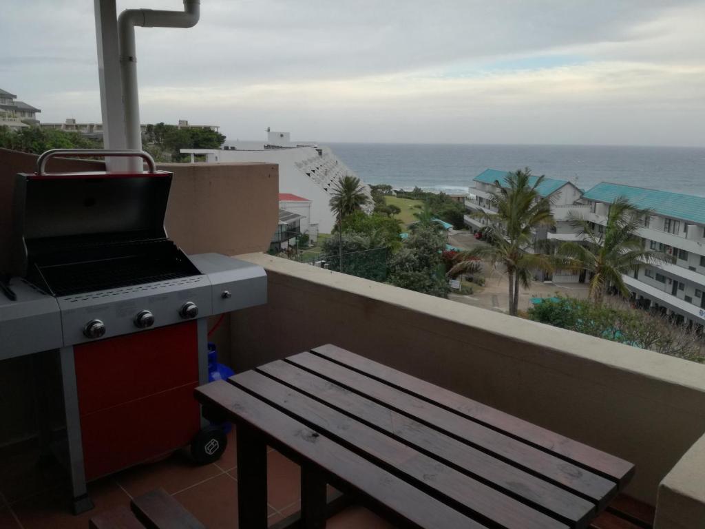 a grill and a bench on a balcony with the ocean at Ithaca Beach Resort in Margate