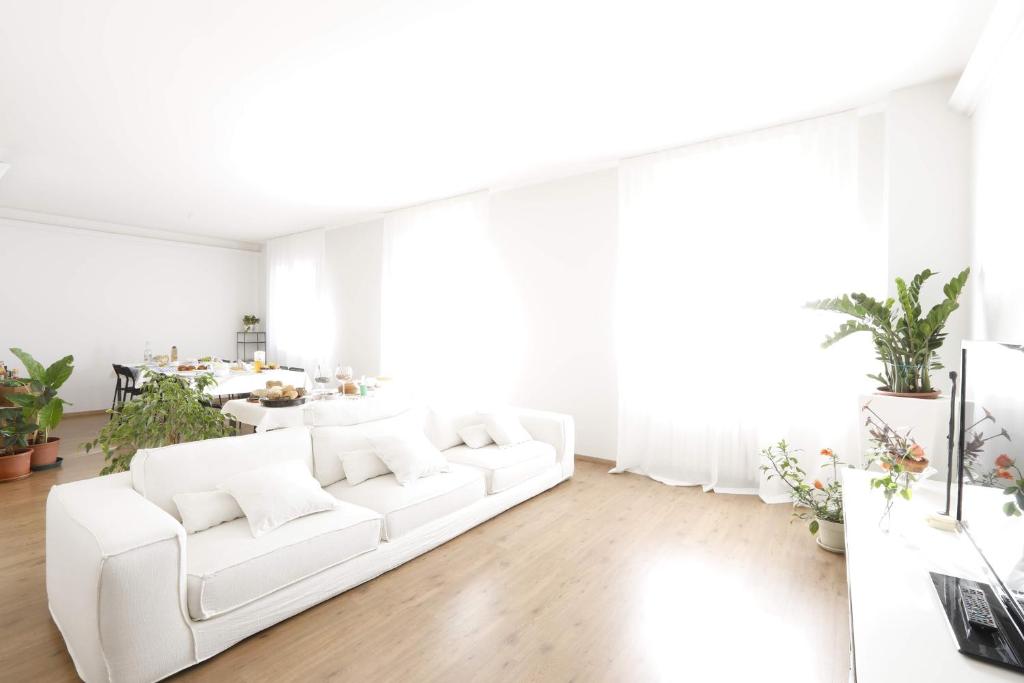 a white living room with a white couch and a table at Pisacane61 B&B in Modena