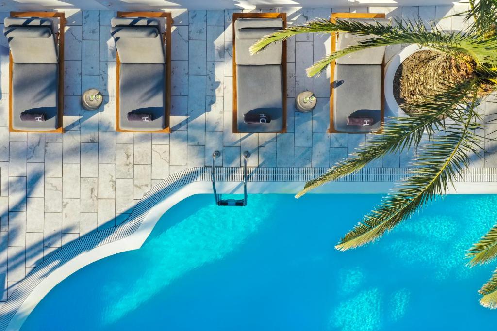 una vista sul tetto di una piscina con acqua blu di Strogili Hotel - Adults Only a Kamari