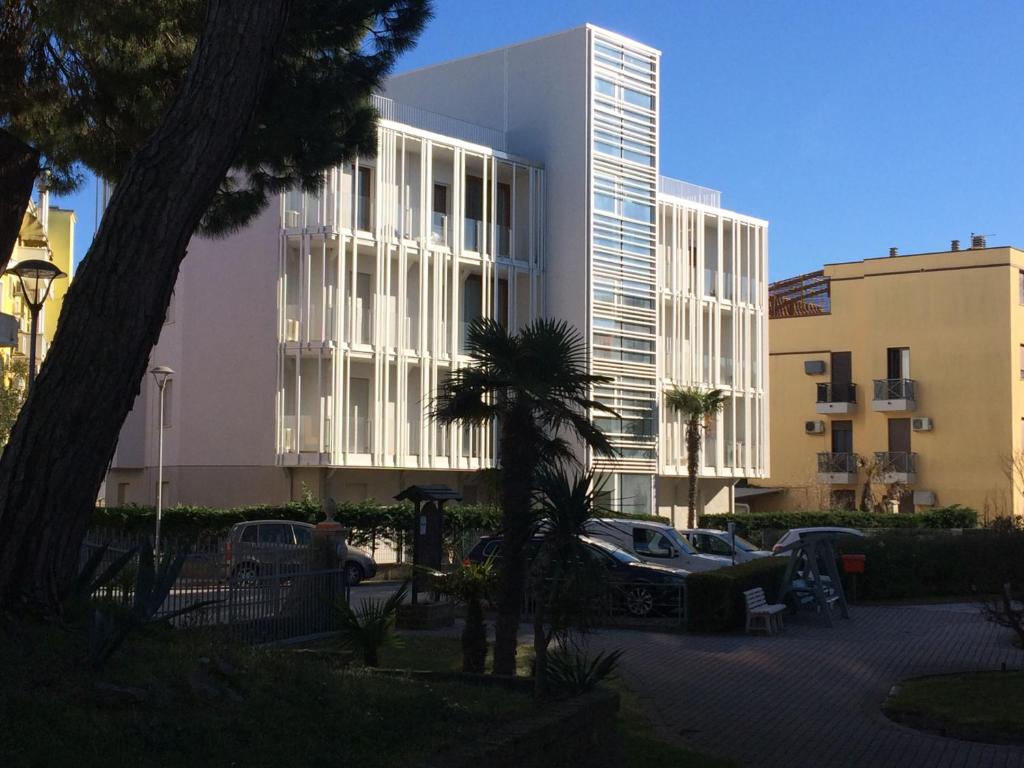 un gran edificio con coches estacionados en un estacionamiento en Milan Residence, en Rosolina Mare