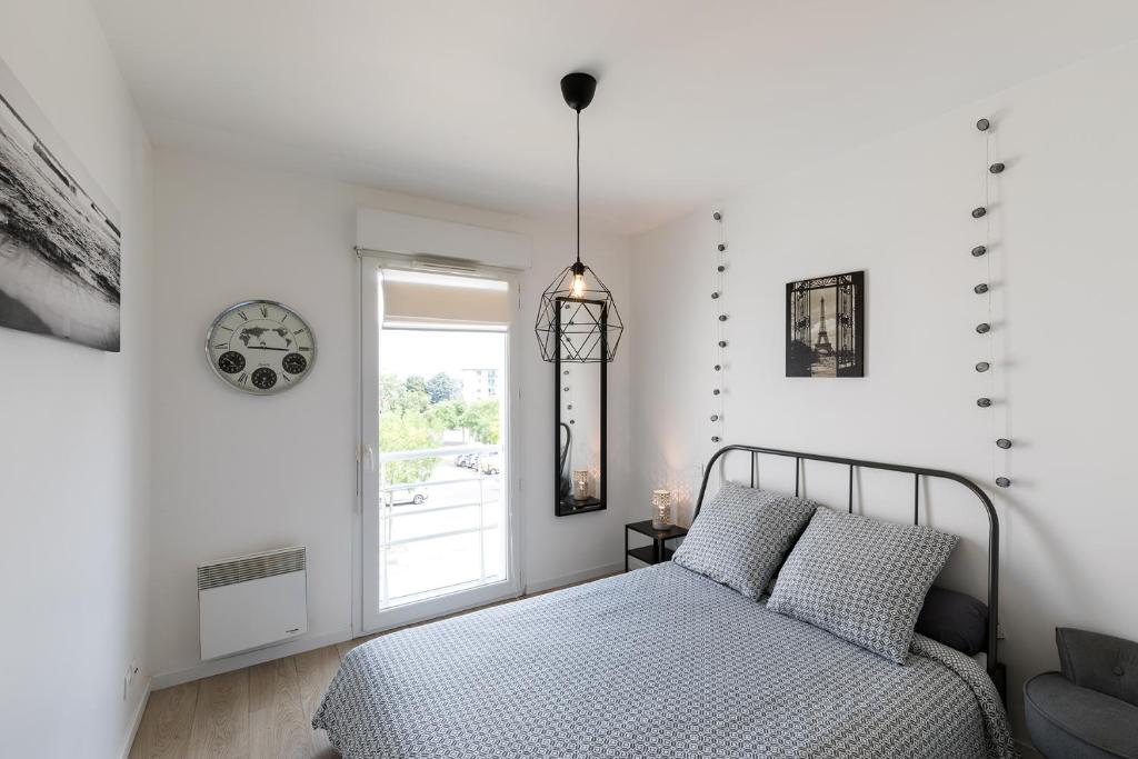 a white bedroom with a bed and a window at South West in Anglet